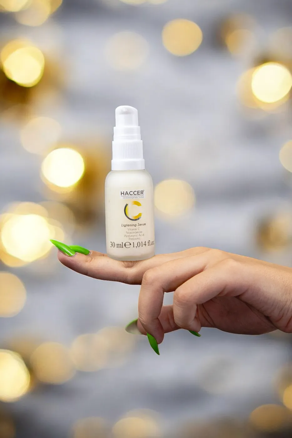 Arkası bulanık ışıklı fonda, açık avuç içinde duran küçük serum şişesi